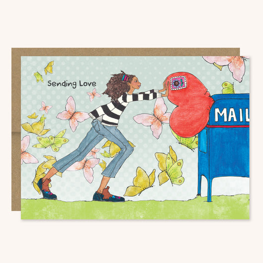 Sending Love Greeting Card featuring a brown girl shoving a giant heart into a blue mailbox.