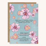 back of blue greeting card with pink flowers. It reads brown crayons is a multiracial company. we strive to reflect, represent and empower all girls of color. 