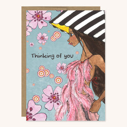 Thinking of you greeting card featuring a brown girl wearing a black and white striped hat and shirt made of feathers. 